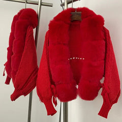 Front view of a red knit jacket with plush faux fur panels and V-neck opening, hanging on a rack in studio light.