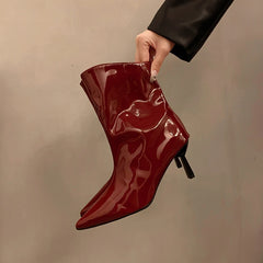 Red glossy high heel ankle boots on neutral background