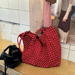 Large red polka dot canvas tote bag on wooden bench