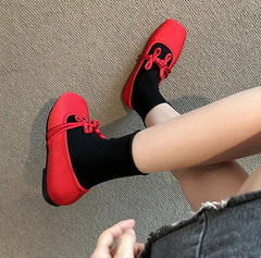 Red satin Mary Jane flats with bow detail on carpeted floor