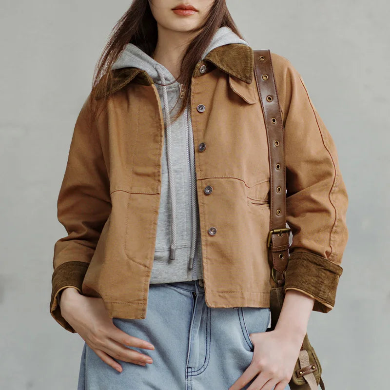Person wearing a brown jacket with leather straps on a plain background