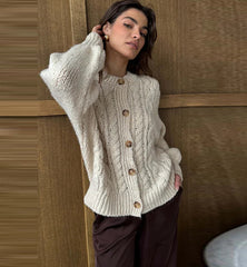 Detail shot focusing on ribbed hem and cuff finish on the beige cable-knit cardigan, showing the knit structure and tidy edge stitching.