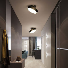 Modern round LED ceiling light with a copper finish and a warm glow, mounted on a ceiling in the lobby of a well furnished apartment.