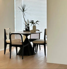Dining room with a black table and chairs, plants, and a chandelier.