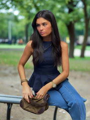 Woman sitting on a bench wearing stacked ruffle hem peplum top for polished jeans-and-heels looks holding a brown bag .