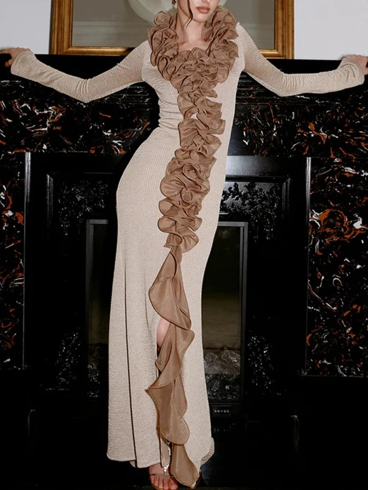 Model wearing a floor-length gown with cascading ruffle detailing, posed elegantly in a formal interior setting