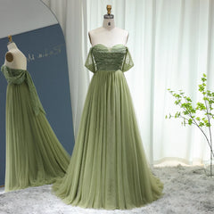 A woman modeling a sage green A-line gown with an off-shoulder neckline.