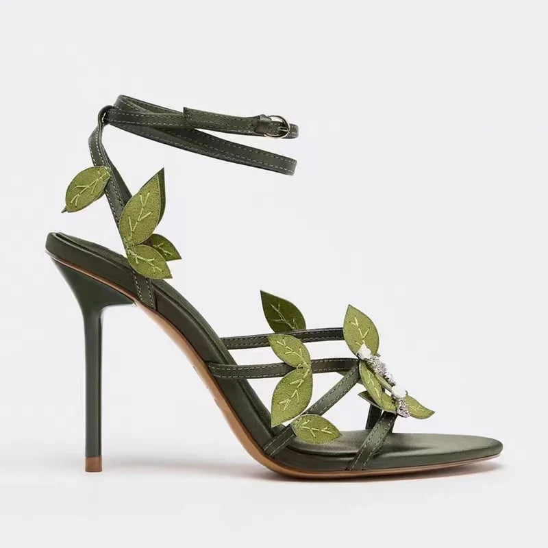 Green high-heeled sandal with leaf designs on a white background