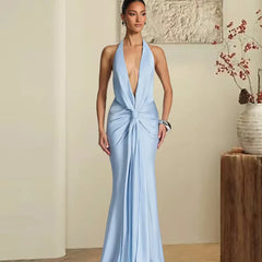 Woman wearing a light blue satin halter knot maxi dress in an elegant indoor setting.