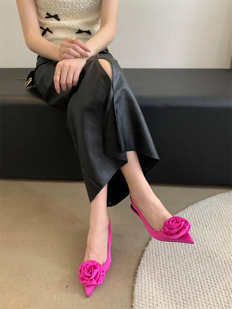 A woman wearing a pair of satin slingback pumps with a flower design.