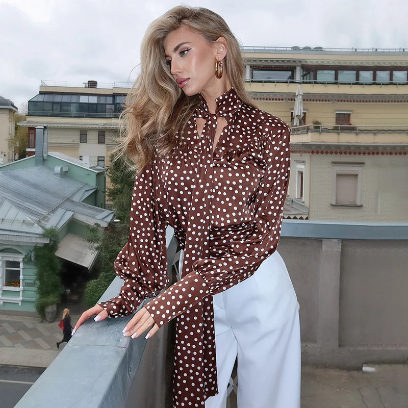 Close-up of satin blouse showing tie-neck bow, printed pattern, and lantern sleeve detail.