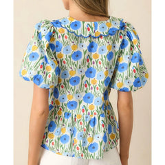 Woman wearing a vintage-inspired floral blouse, perfect for soft spring looks, on a beige background
