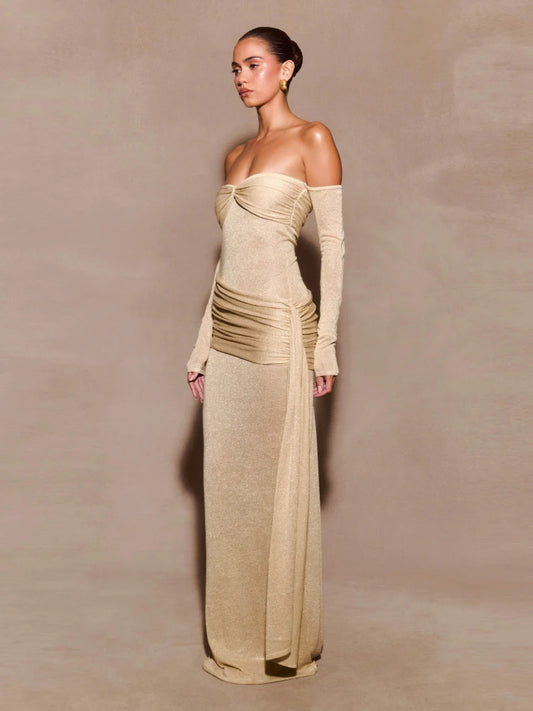Woman wearing a formal off-shoulder gown styled for red carpet events against a plain background