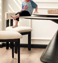 Child sitting on a chair at a dining table in a home setting