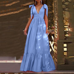 A model wearing a Blue deep V neck bow tie maxi dress with cap sleeves and a pleated skirt.