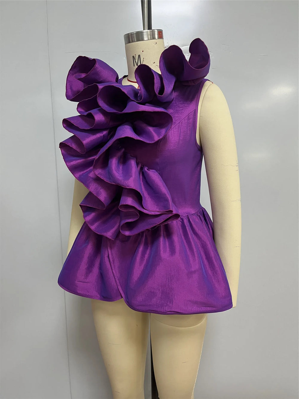 Purple ruffled dress on a mannequin against a plain background