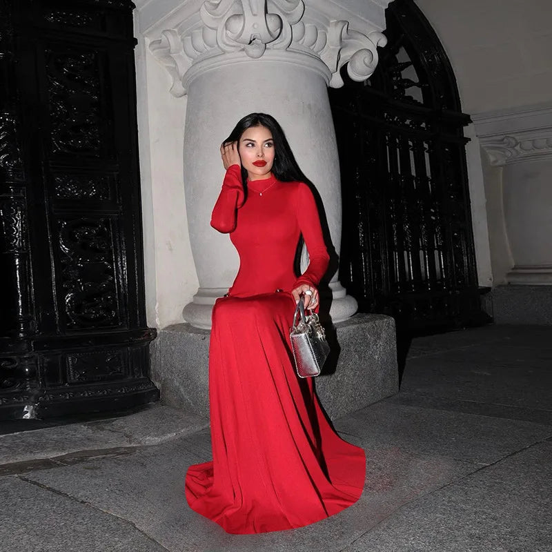 Woman in a  shirring empire waist gala maxi dress in vibrant red for a statement looks, standing in an elegant architectural setting