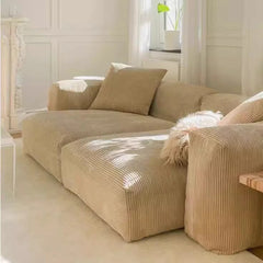 “Side view of L-shaped beige sofa with natural light and modern decor”


