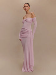 Side view of a woman wearing an elegant, sculpted gown with full-length sleeves against a beige background