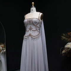 Cape sleeve formal gown with embellished top and soft tulle drape against a dark backdrop