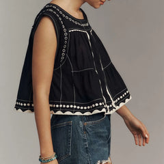 Black and white vest top paired with denim shorts worn by a person on a plain background
