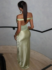Woman in a light green off-shoulder dress standing against a plain background