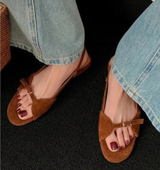 Brown sandals worn with light blue jeans on a dark surface