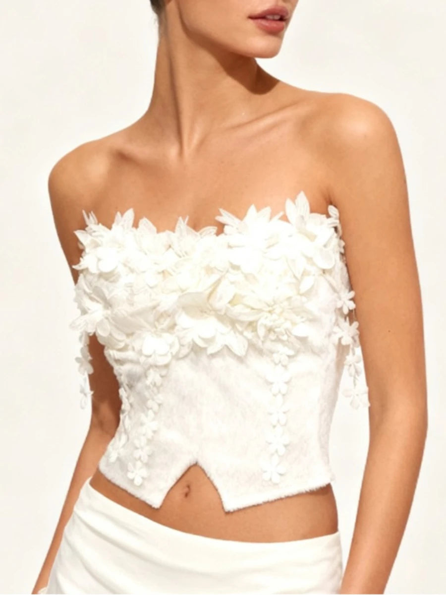 White strapless top with floral embellishments, revealing smocked construction that adds flexibility while maintaining a sculpted fit.