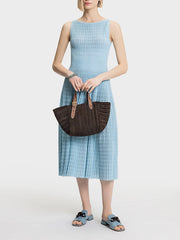 A woman modeling a solid A-line sleeveless midi dress with draped details.