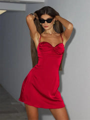 Woman in a Spaghetti strap red mini dress with a softly ruched bust against a gray background