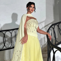 Woman in a light yellow traditional outfit with a white dupatta standing on a staircase.