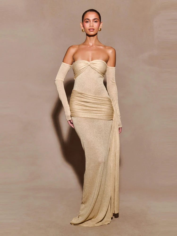 A woman wearing a strapless beige draped evening gown with a sculpted fit on a plain background