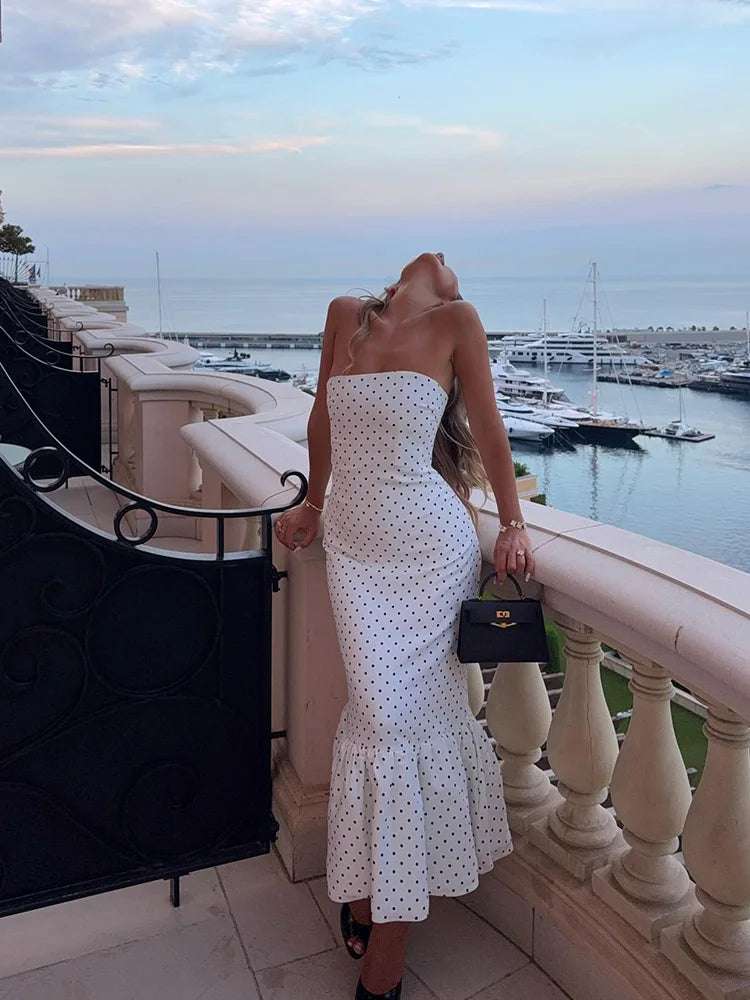woman in a white strapless polka dot mermaid maxi dress on a balcony