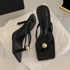 Black high-heeled shoes with gold accents on a white surface