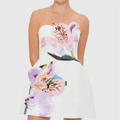A woman wearing a strapless A-line mini styled for summer events in a white background.