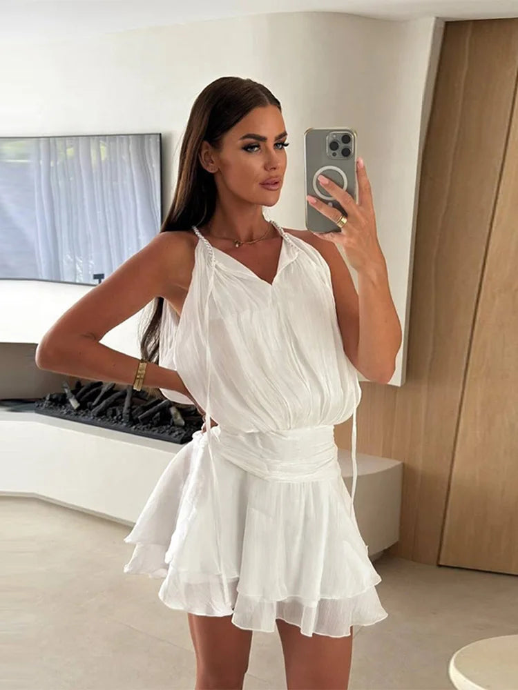 A woman takes a mirror selfie wearing a summer dress with a ruffled hem and a relaxed fit in a modern room.