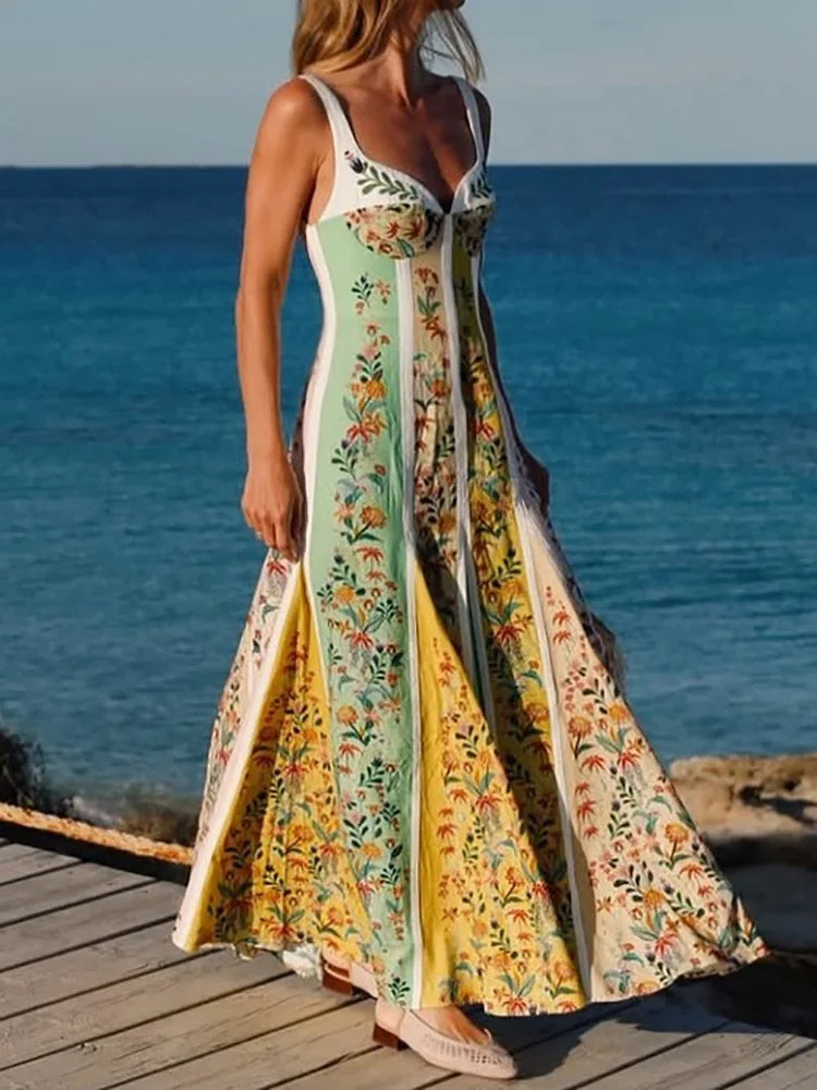 Woman in a patchwork V-neck maxi dress with flowing A-line skirt standing on a wooden deck by the ocean.