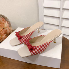 Sweet cottagecore mixed colour heels for women’s summer outfit on a white platform with a floral arrangement in the background.