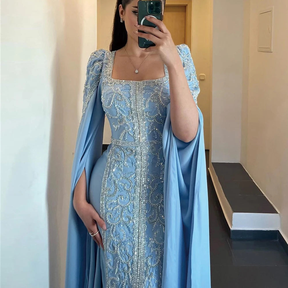 A woman modeling a teal satin mermaid gown with a square neckline.