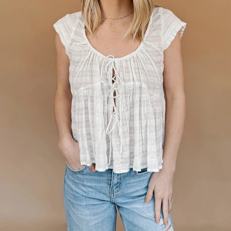 A woman modeling a tie-front smocked crop top.