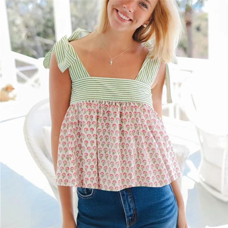 Woman wearing tie-strap babydoll tank with leaf print hem and striped bodice standing outdoors.