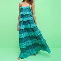 A woman modeling a tiered ruffle cami dress with a sleeveless design.