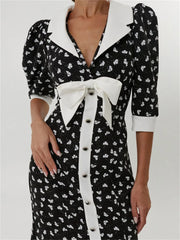 Close-up of V-neck dress with white contrast trim and bow detail