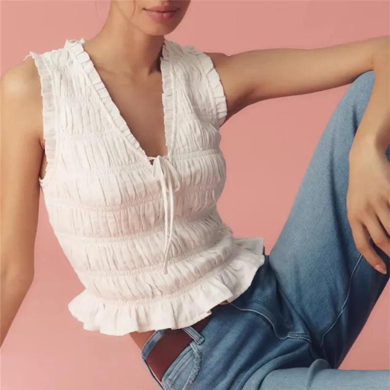A woman modeling a V-neck smocked tank top with a bow tie front.