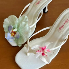 White high-heeled shoes with floral decorations on a wooden surface