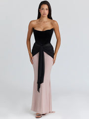 Strapless velvet corset dress with dramatic tie detail for a refined evening look.