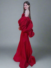 Woman in a red evening gown standing in front of a  gray backdrop