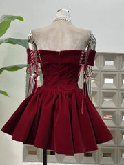 Side angle highlighting the structured waist and full pleated skirt volume of a burgundy velvet mini party dress.