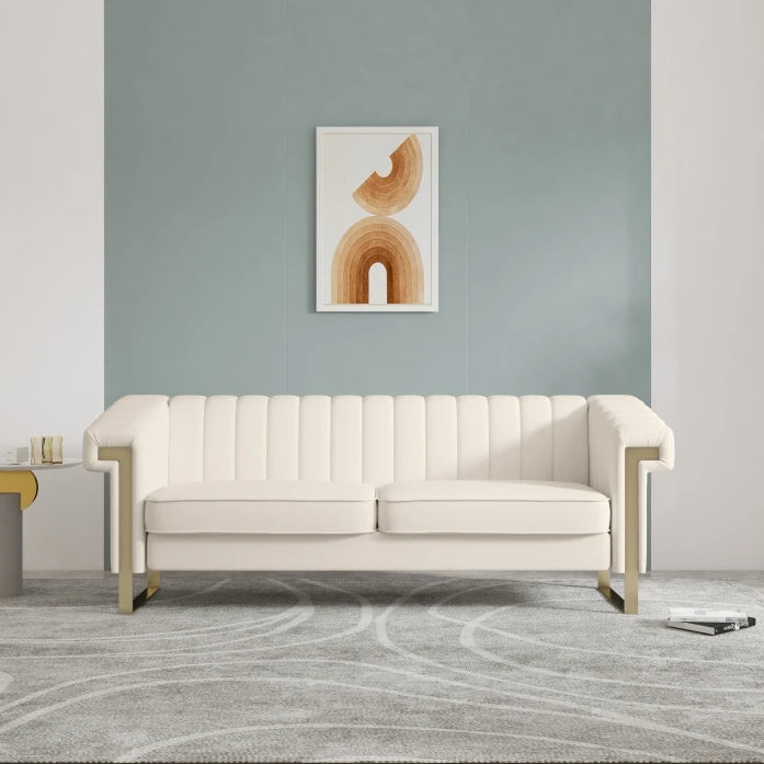 A beige velvet long couch Chesterfield sofa with a chaise, displayed in a room with a green wall and a framed abstract picture above it, alongside a stainless steel end table.