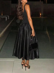 Voluminous black midi dress paired with silver heels and bag